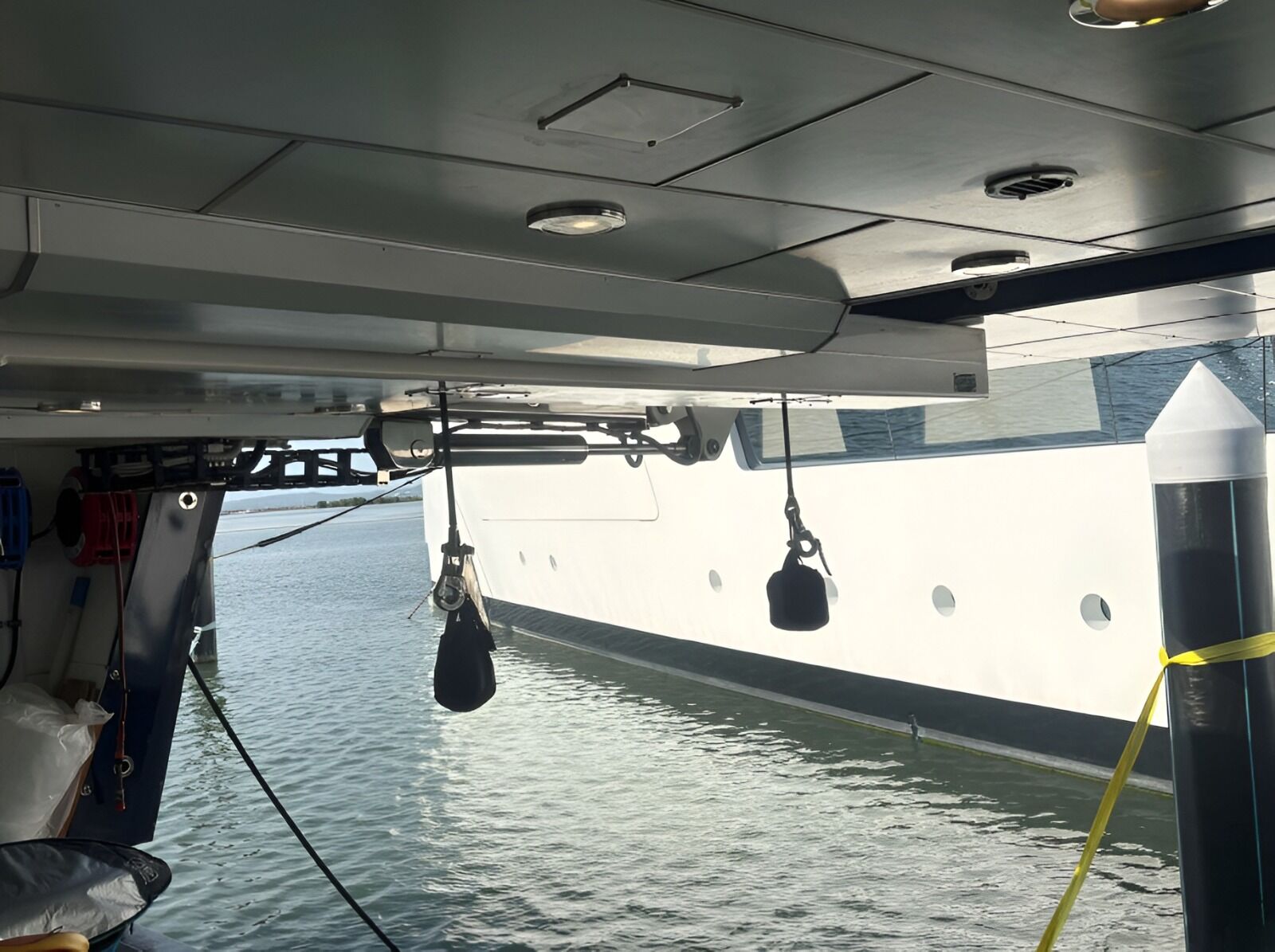 Fall blocks and hooks hanging from a davit under a yacht's deck