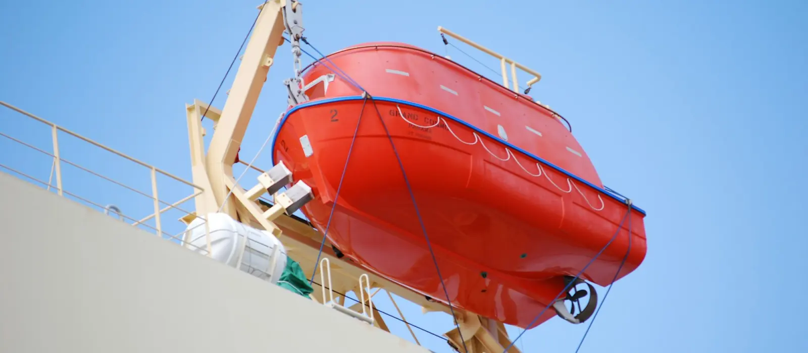 An enclosed lifeboat stowed in its davit on a ship's side