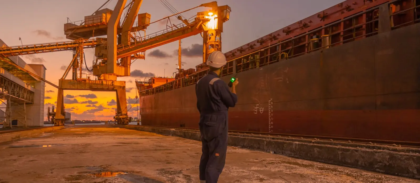 A man on the quay checking a bulk carrier alongside at dusk